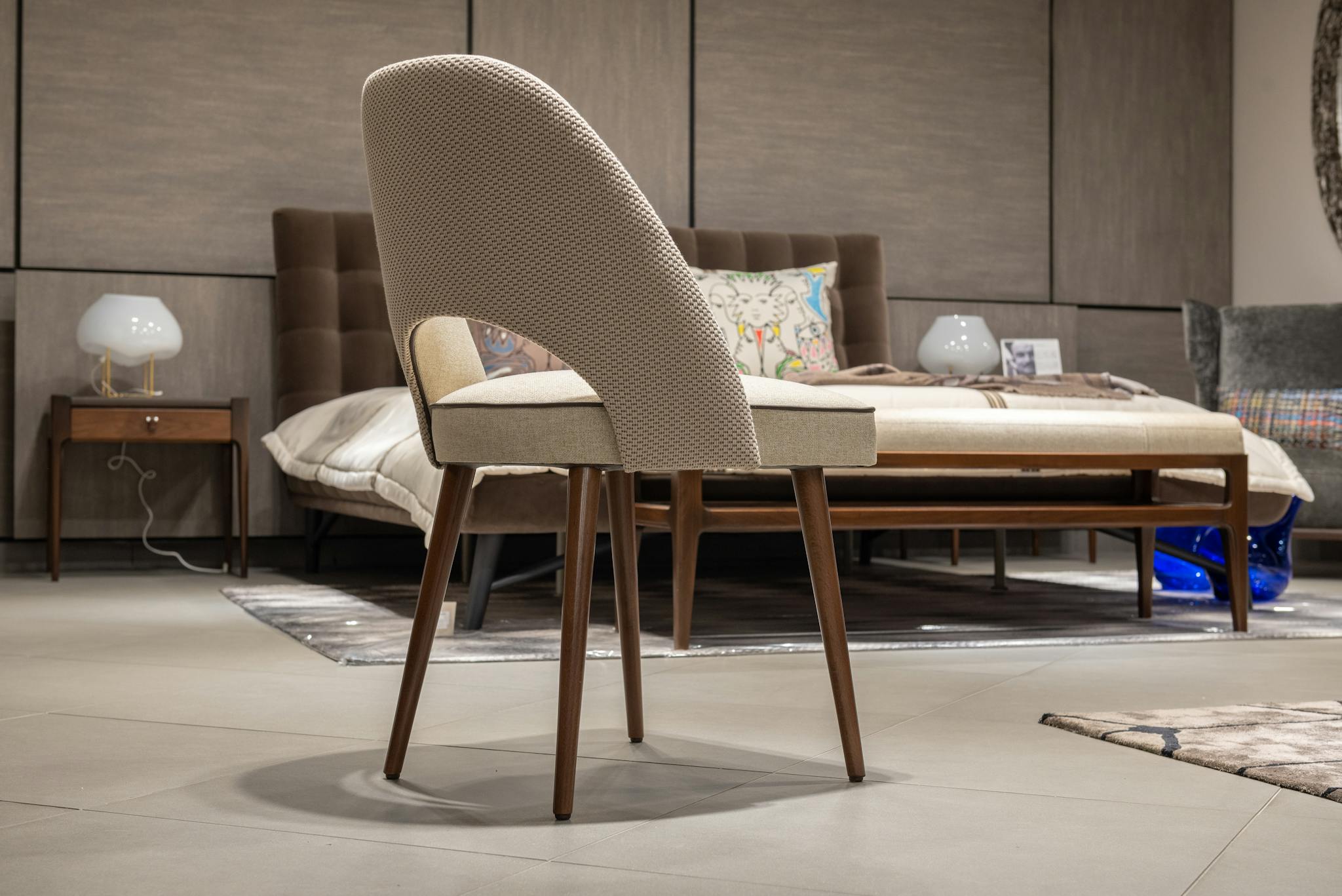 Elegant modern bedroom featuring cozy chair, stylish bed, and contemporary decor with soft lighting.