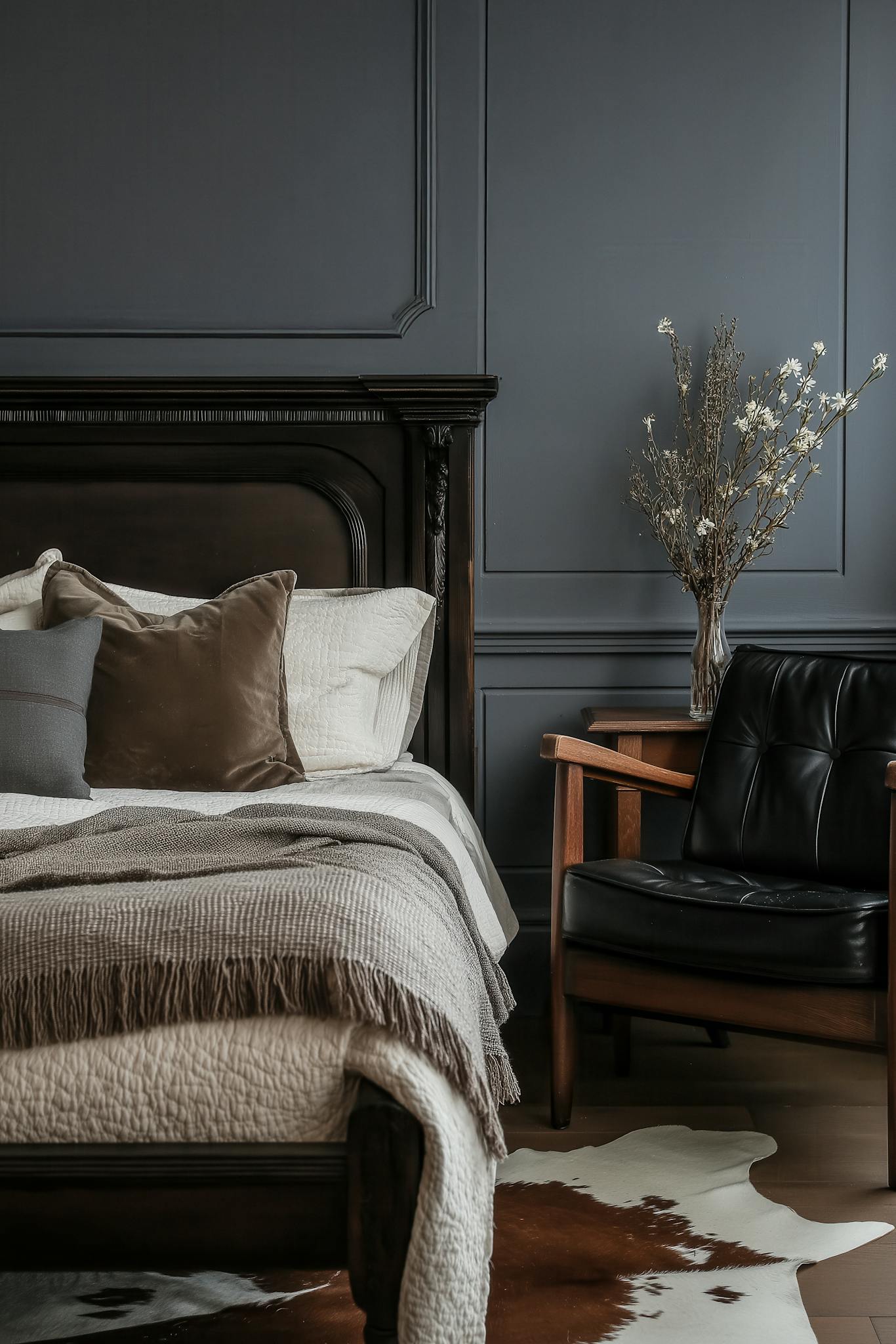 Stylish dark-themed bedroom with elegant decor, luxurious bed, and cozy armchair.